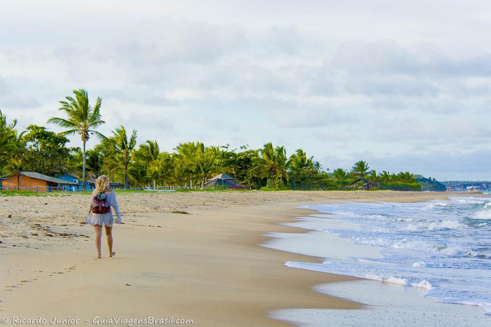 Imagem de uma moça loira caminhando na Praia de Caraiva.